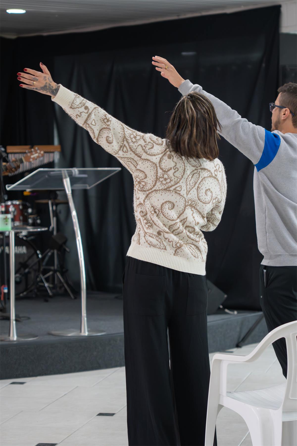 Uma irmã adorando de braços abertos no culto